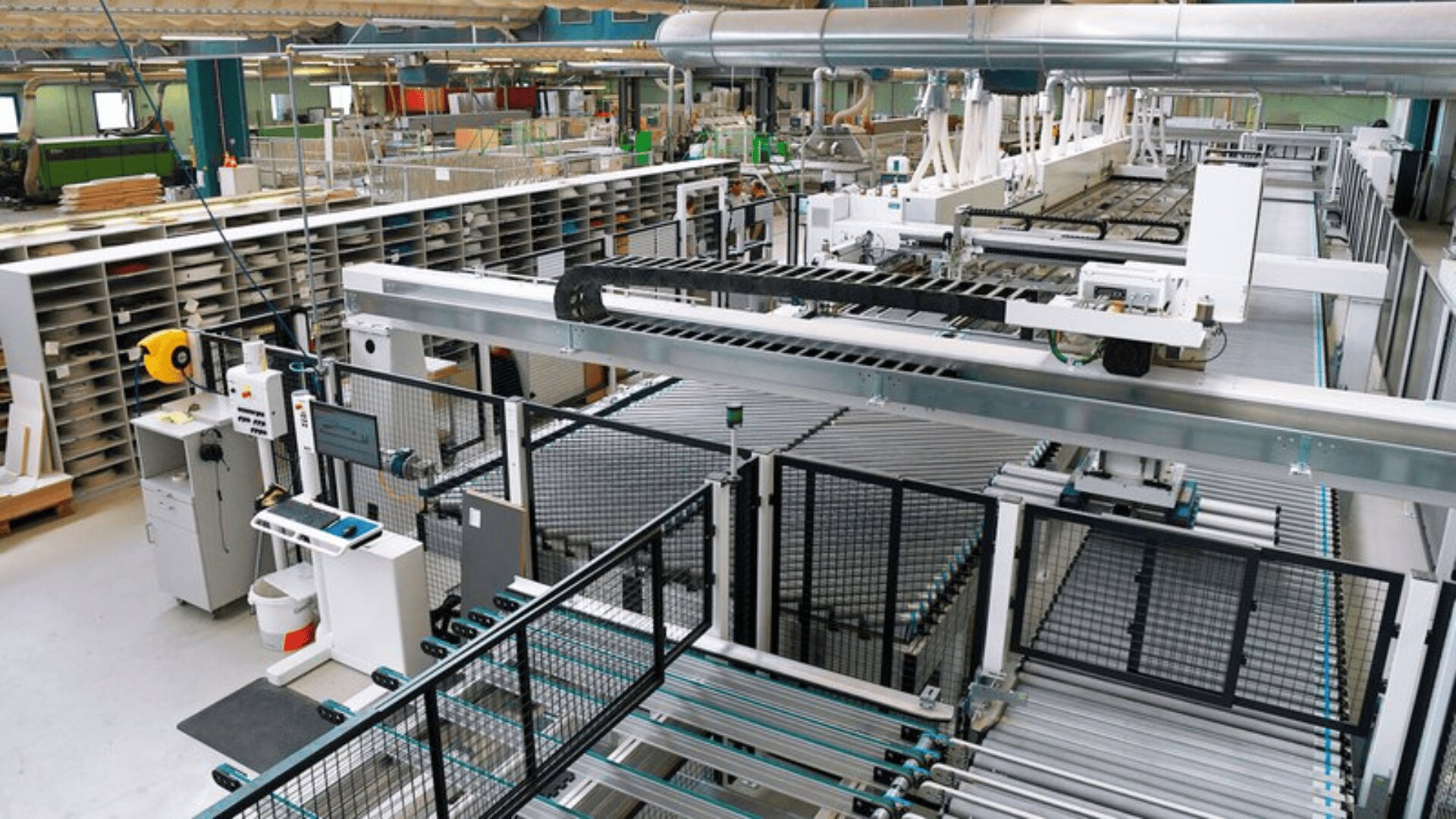 Ein modernes Fabrikinterieur mit automatisierten Maschinen, Förderbändern und Arbeitsplätzen, umgeben von Regalen und industriellen Geräten in einer gut beleuchteten, geräumigen Produktionsumgebung.