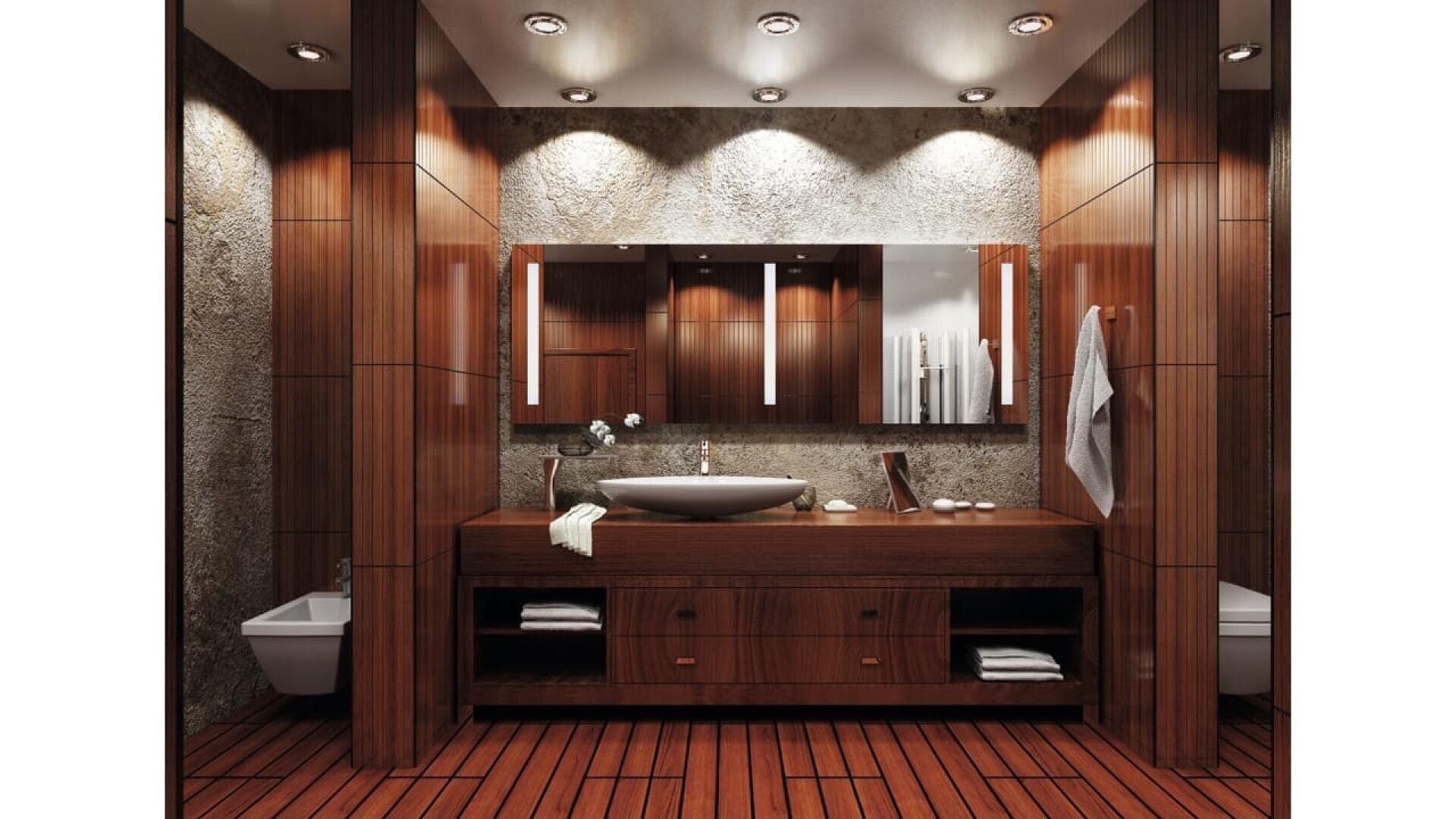 Salle de bains moderne avec des murs et un sol en bois, un grand meuble-lavabo avec vasque, un large miroir, un éclairage encastré et un décor minimaliste. La serviette est accrochée au mur, les toilettes et le bidet se trouvant de part et d'autre.