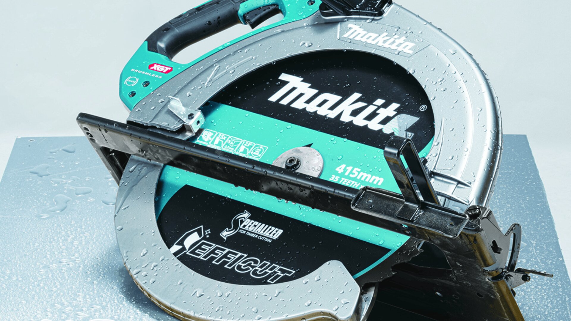 Eine Nahaufnahme einer Makita 415-mm-Kreissäge mit Wassertropfen auf der Oberfläche, die das Markenzeichen und die Details, einschließlich des Blattes und des Griffs, zeigt.