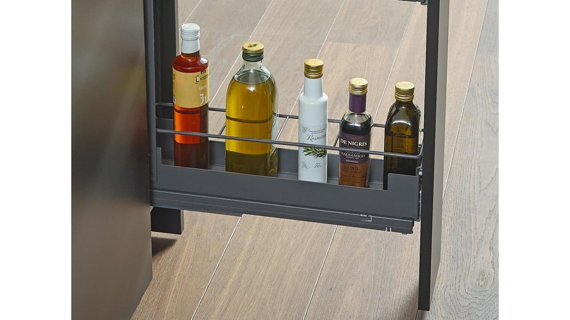 Une étagère de cuisine coulissante contenant cinq bouteilles d'huile et de vinaigre, posée sur un sol en bois clair.