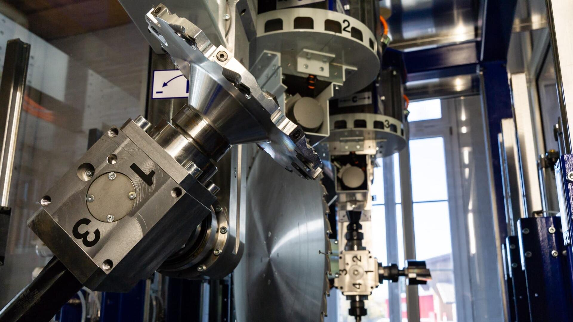 Nahaufnahme eines industriellen CNC-Bearbeitungszentrums mit mehreren Metallwerkzeughaltern, die mit Nummern gekennzeichnet sind, in einer hell erleuchteten Anlage.