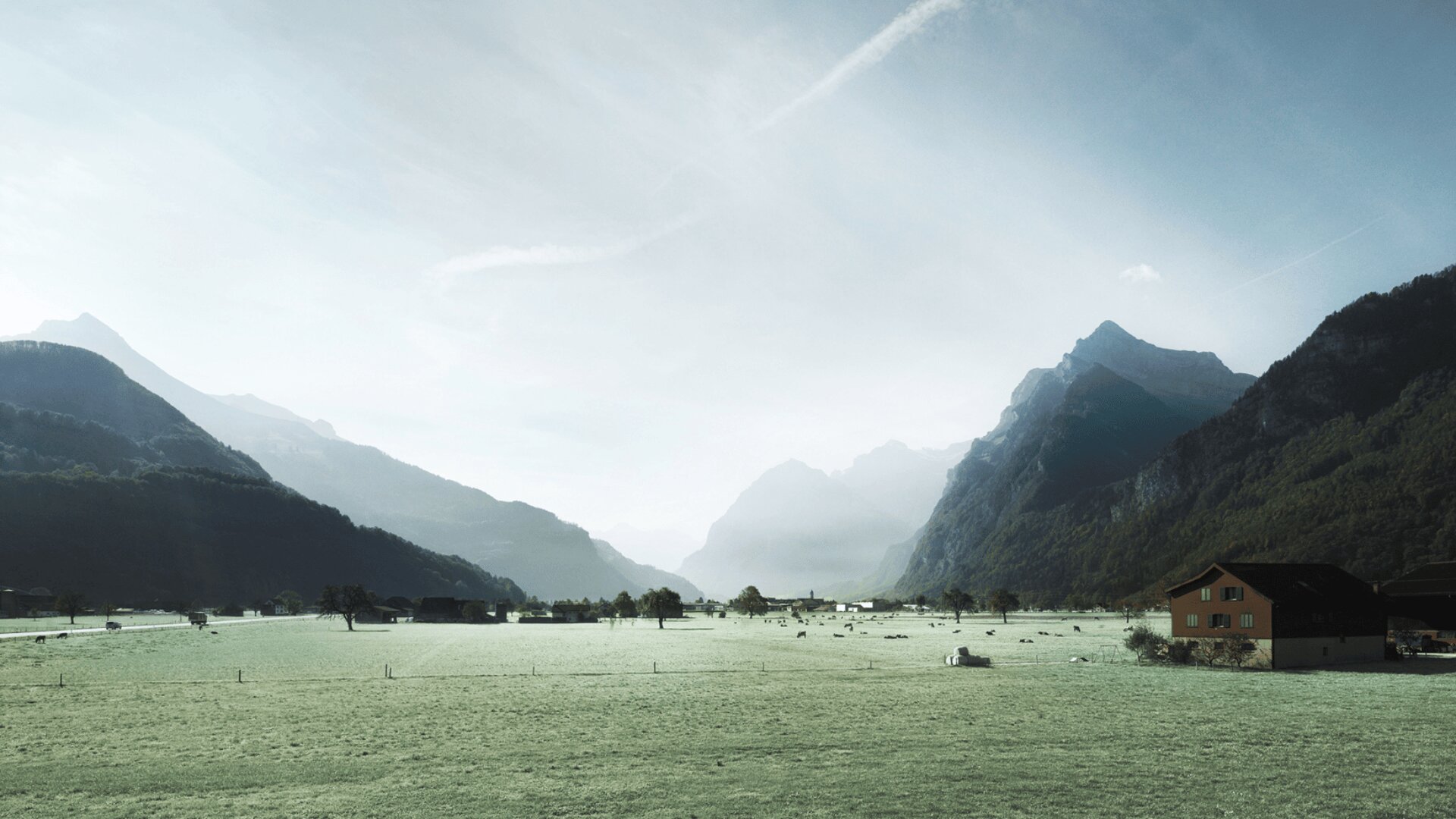 Ein malerisches Tal mit grünen Feldern, verstreuten Häusern und grasenden Tieren, umgeben von hohen, felsigen Bergen unter einem wolkenverhangenen Himmel, durch den das Sonnenlicht scheint.