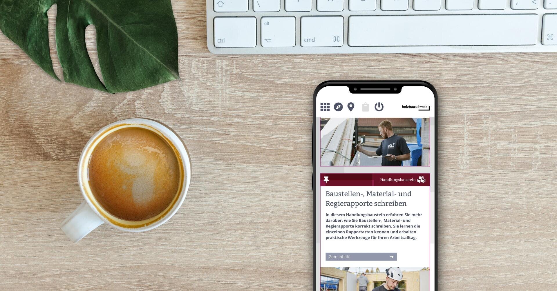 Eine Tasse Kaffee, eine Tastatur und ein grünes Blatt liegen auf einem hölzernen Schreibtisch neben einem Smartphone, auf dem eine Website über Konstruktion, Materialien und das Schreiben von Baustellenberichten angezeigt wird.