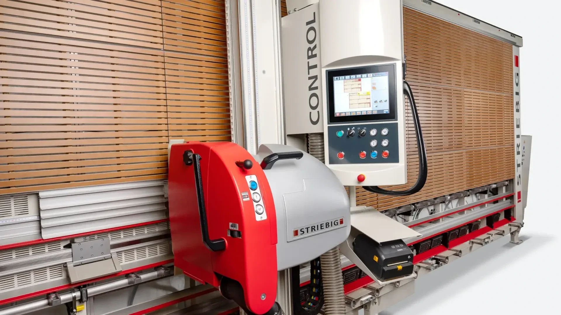 Gros plan sur une scie à panneaux verticale Striebig CONTROL avec panneau de commande électronique, boîtier rouge et gris et panneaux de bois derrière la machine.