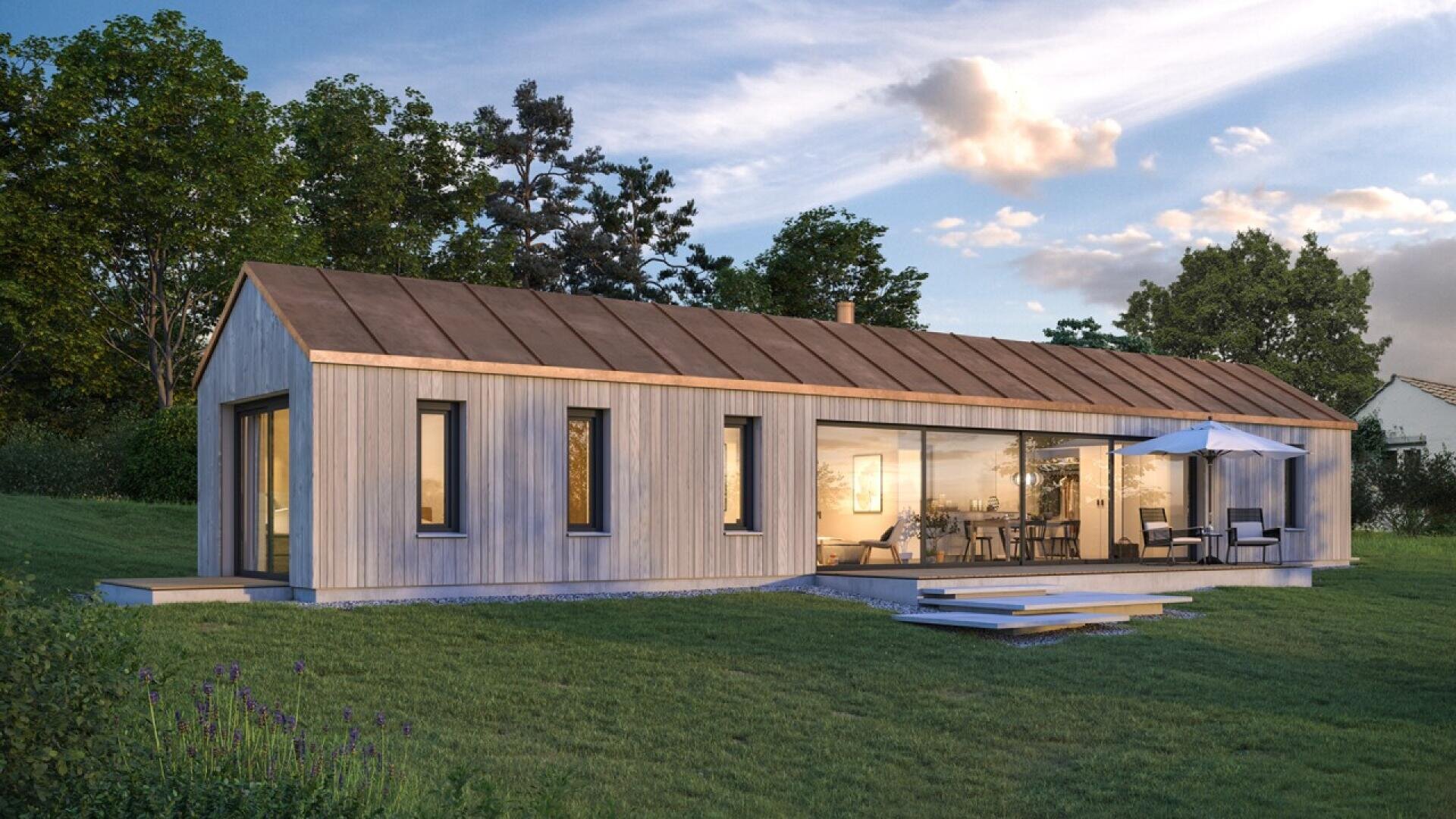 Une maison moderne à un étage, avec un bardage en bois, de grandes fenêtres en verre et un toit en pente, située sur une pelouse avec des sièges extérieurs et entourée d'arbres sous un ciel partiellement nuageux.