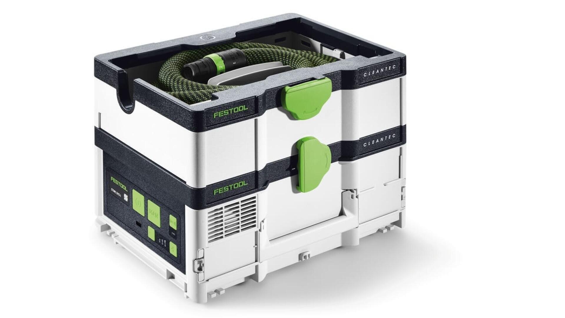 Un aspirateur Festool CLEANTEC compact, blanc et noir, avec des loquets verts et un tuyau vert enroulé, rangé sur le dessus à l'intérieur d'un conteneur modulaire et empilable.