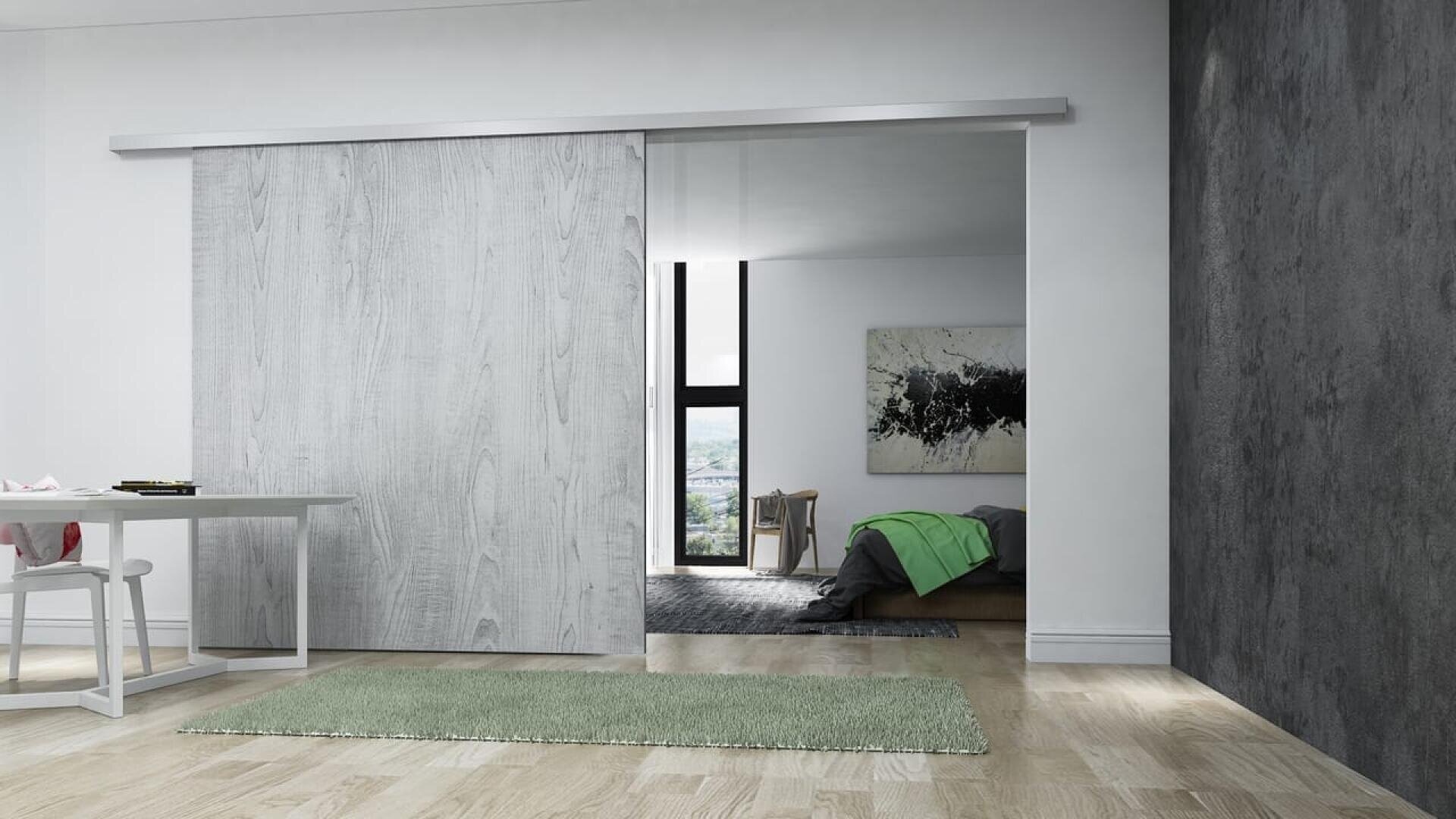 Un intérieur moderne avec une porte coulissante en bois partiellement ouverte, révélant une chambre à coucher avec un lit, une couverture verte, une grande fenêtre et une œuvre d'art abstraite. Au premier plan, une table, un tapis vert et un mur gris texturé.