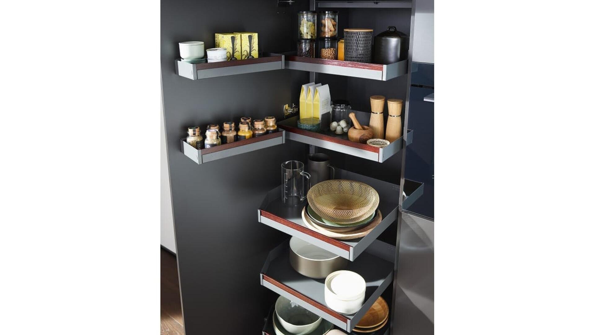 Etagères de cuisine d'angle avec divers objets bien rangés, notamment des bocaux, des bouteilles, des tasses, des bols, des assiettes, une théière et des récipients à épices sur plusieurs étagères noires au design moderne.