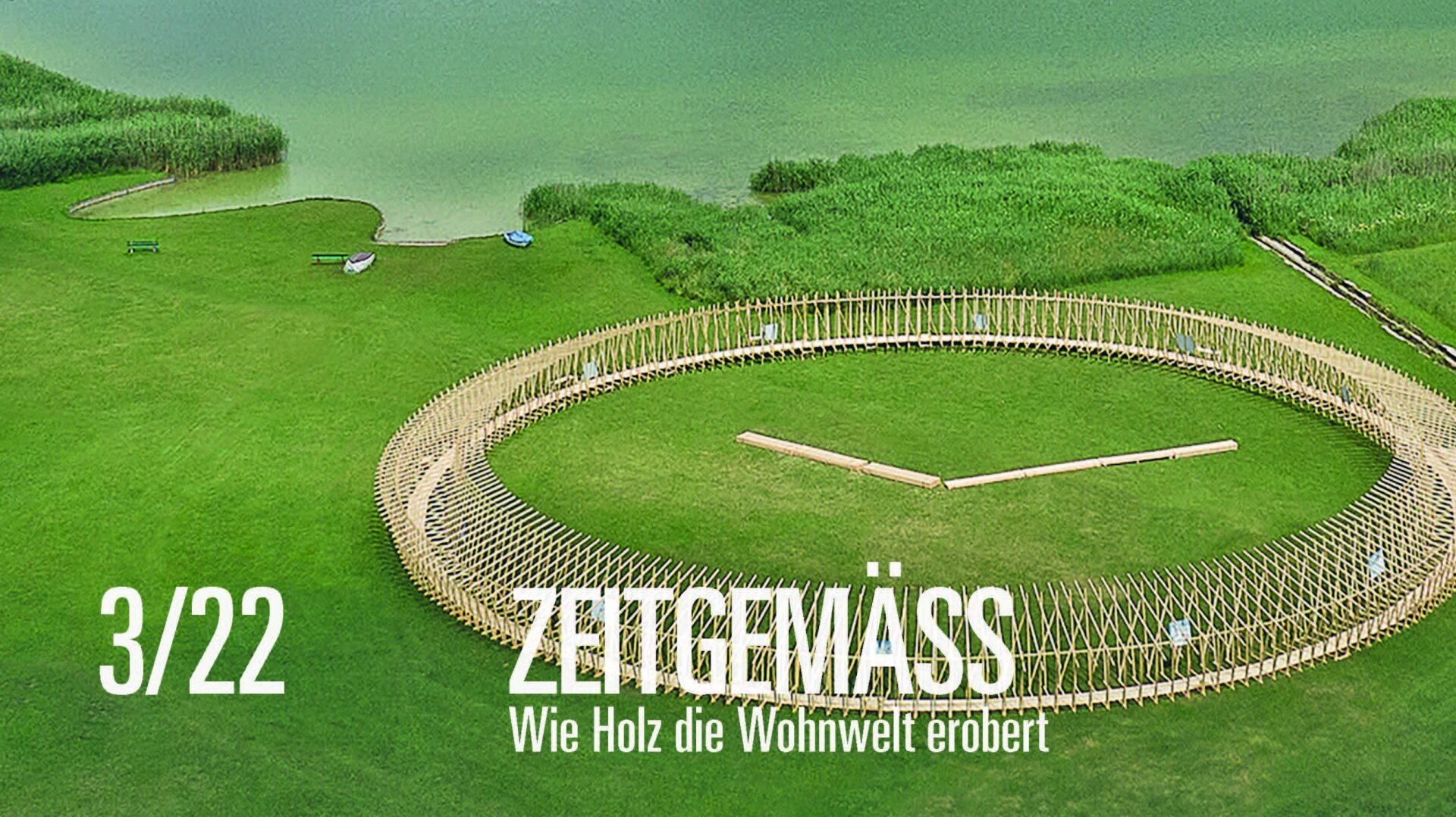 Luftaufnahme einer großen runden Holzkonstruktion auf einem grasbewachsenen Feld in der Nähe eines Sees und Schilfs. Der Text lautet: 3/22 ZEITGEWÄSS Wie Holz die Wohnwelt erobert.