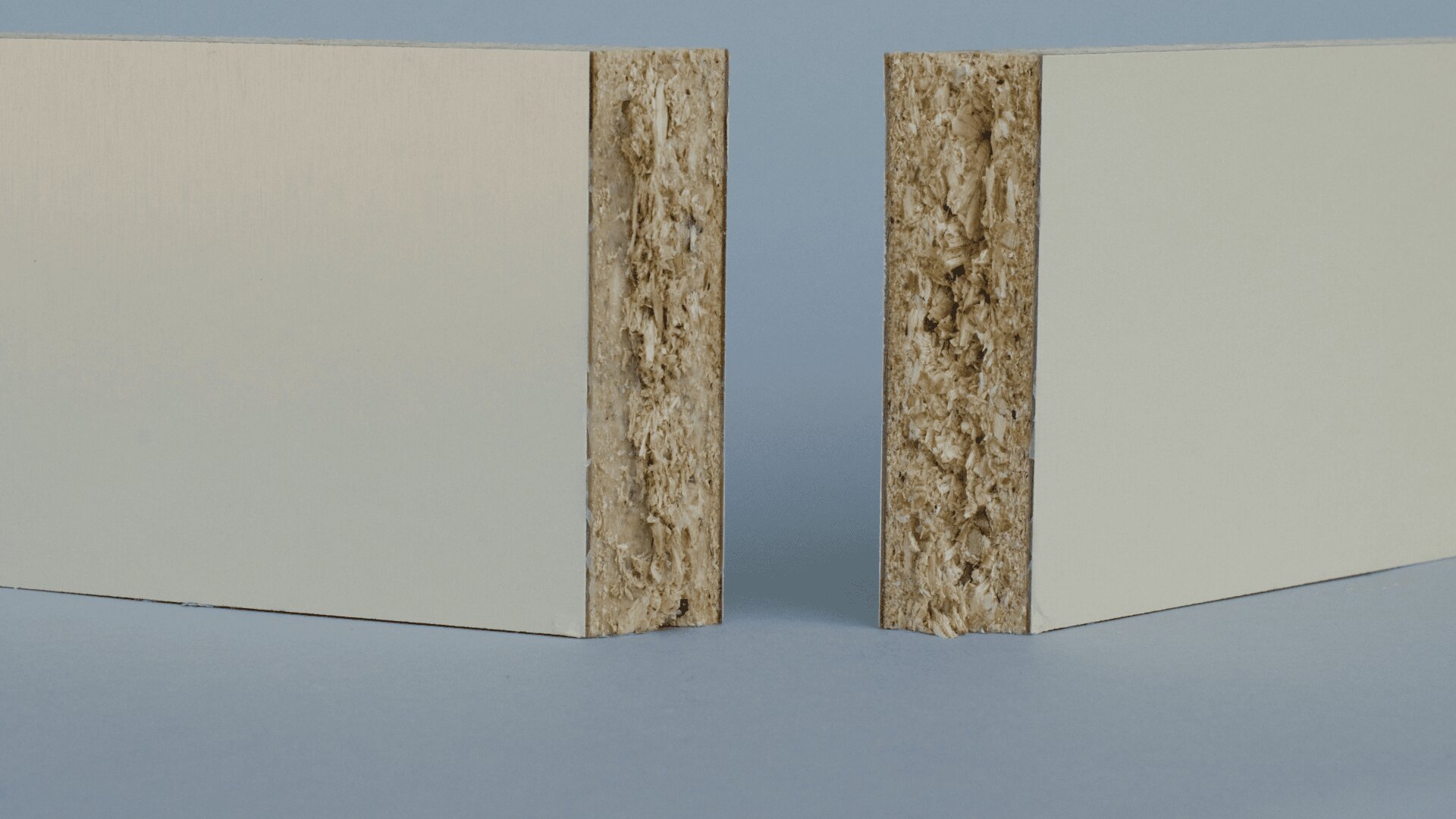 Zwei Spanplatten mit einer glatten, weißen Oberfläche auf einer Seite und sichtbaren, strukturierten Holzspänen auf der Schnittkante stehen aufrecht vor einem neutralen Hintergrund.