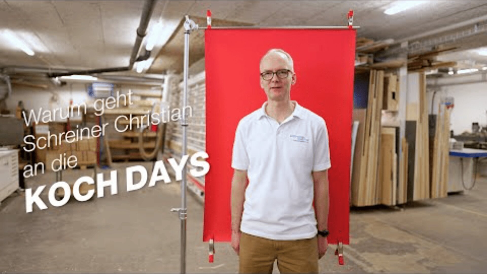 Ein Mann mit Brille und weißem Poloshirt steht vor einem roten Hintergrund in einer Holzwerkstatt. Der deutsche Text lautet: Warum geht Schreiner Christian an die KOCH DAYS.