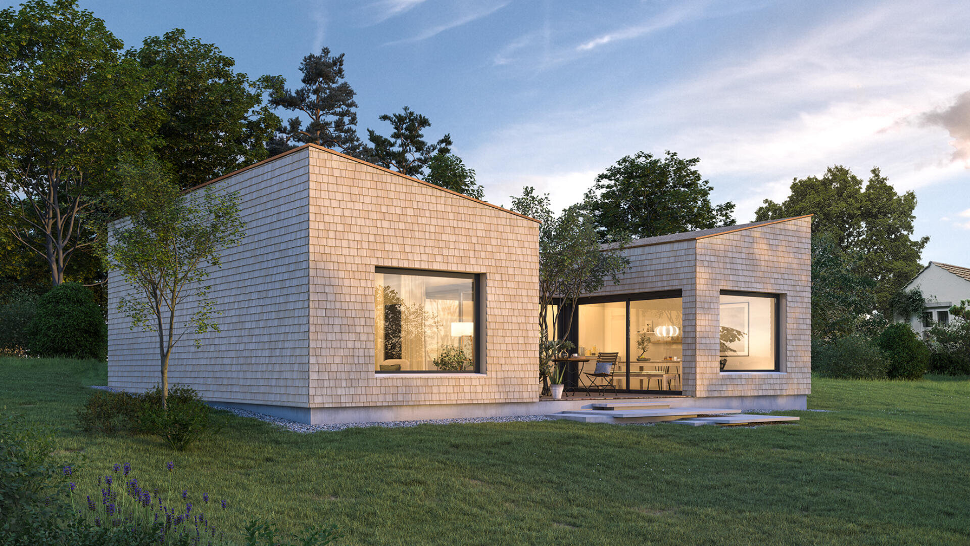 Modernes einstöckiges Haus mit Holzschindeln, großen Fenstern und Flachdächern, umgeben von grünem Gras, Bäumen und sanftem Abendlicht, das aus dem Inneren des Hauses scheint.