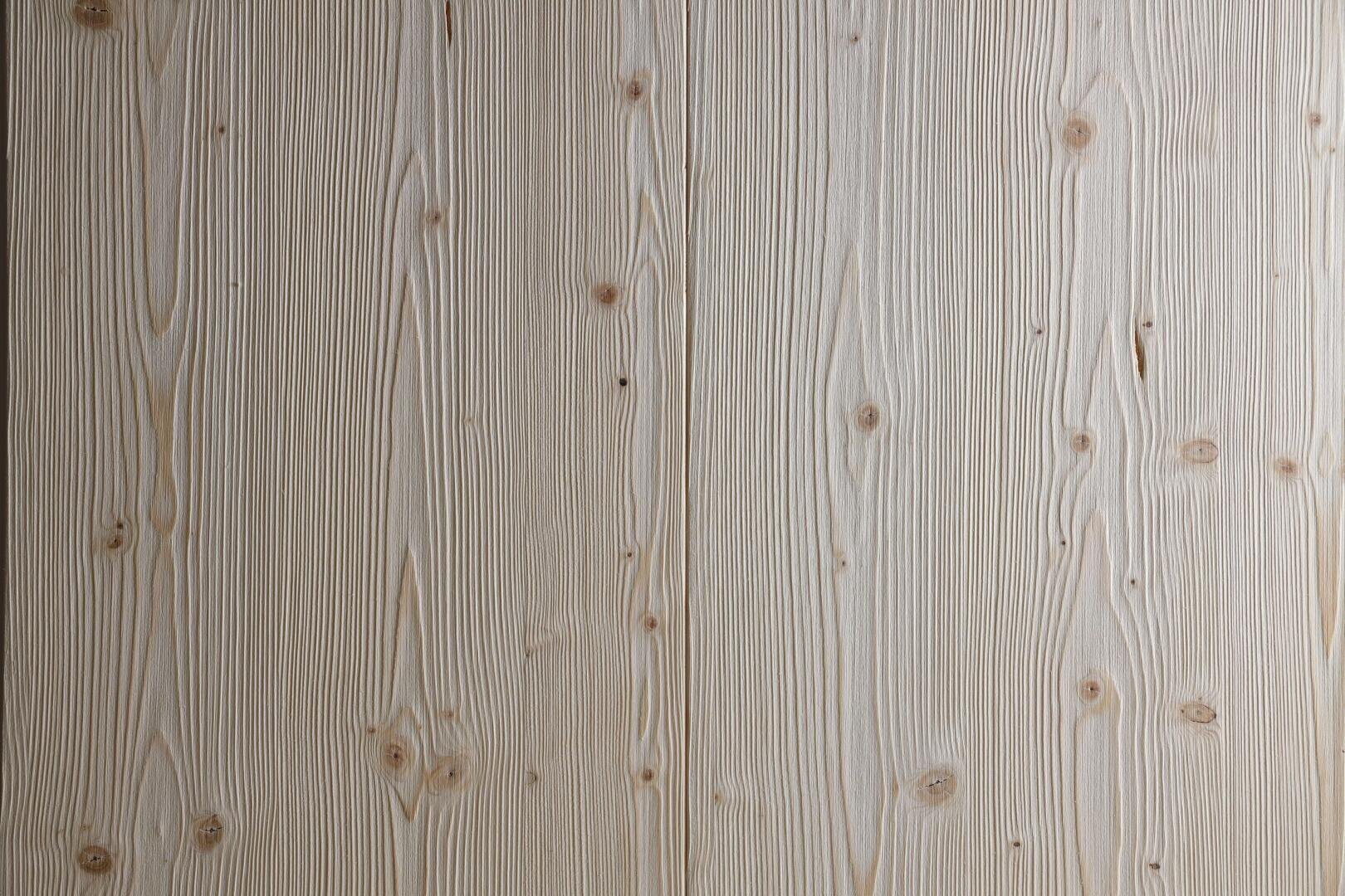 Helle Holzoberfläche mit sichtbaren vertikalen Maserungen und kleinen Ästen, die ein natürliches, strukturiertes Aussehen verleihen. Das Holz hat ein glattes, sauberes Finish und subtile Farbvariationen.
