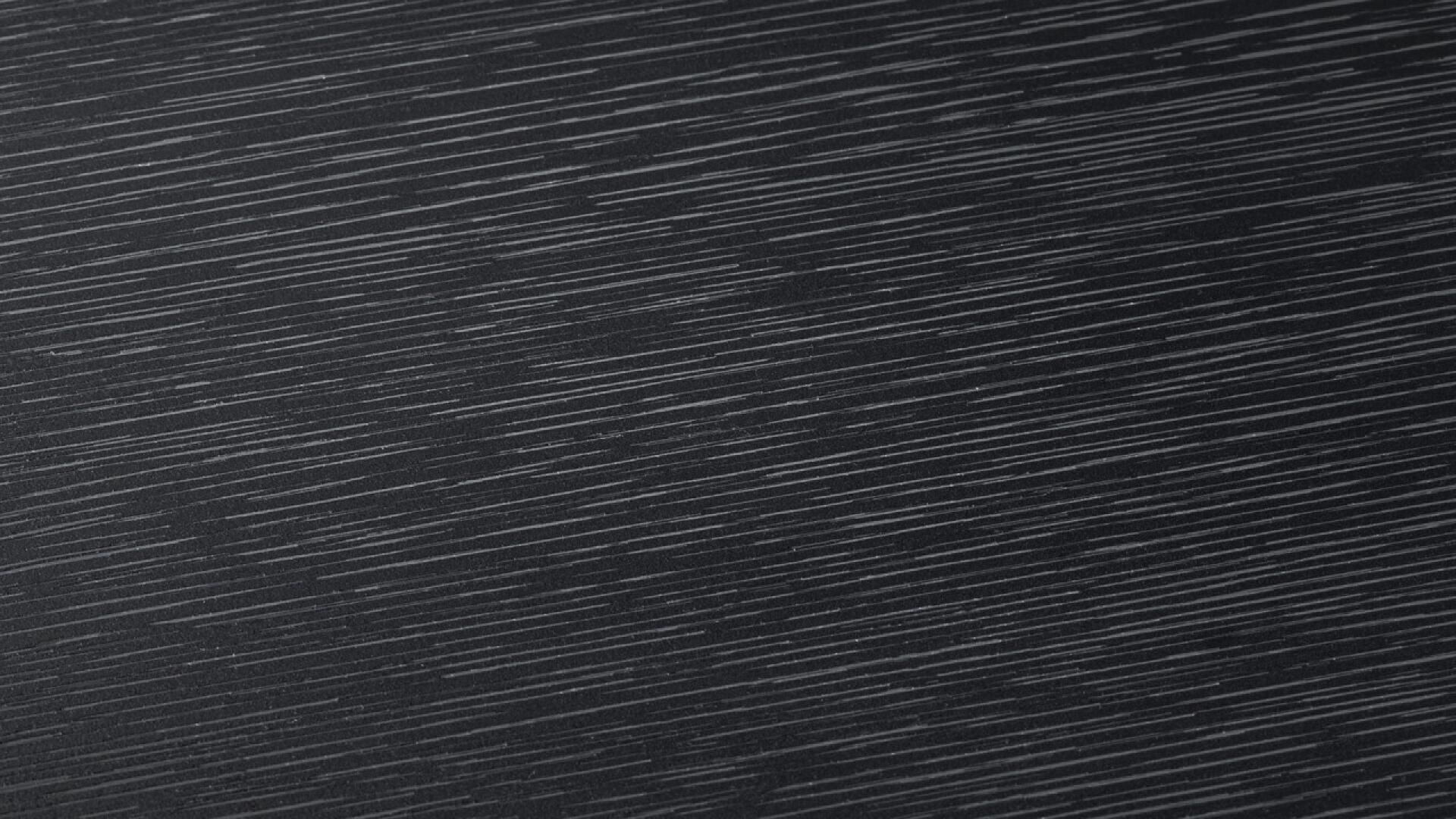 Gros plan d'une surface sombre parcourue de fines lignes blanches diagonales régulièrement espacées, ressemblant à un grain de bois ou à un motif texturé.