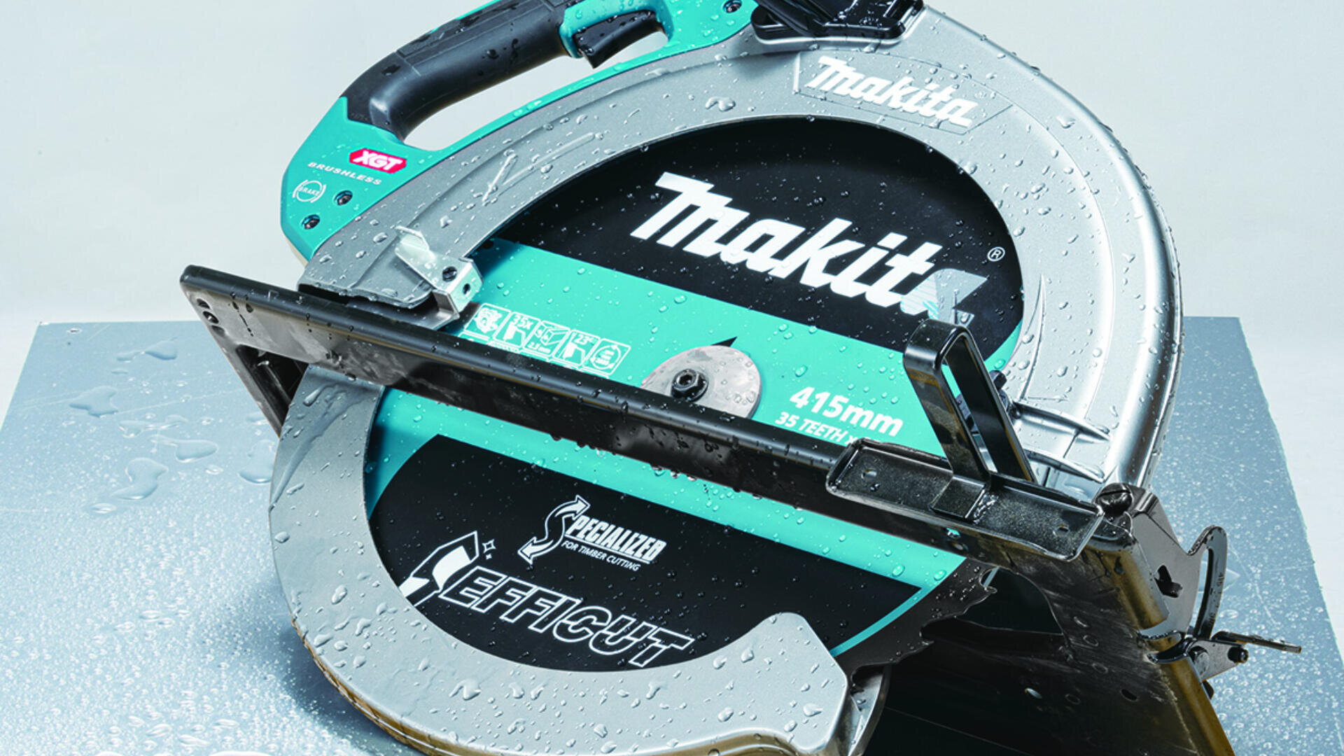 Gros plan sur une scie circulaire Makita avec des gouttes d'eau sur sa surface, mettant en valeur la lame et la marque. L'outil est placé sur une surface métallique.
