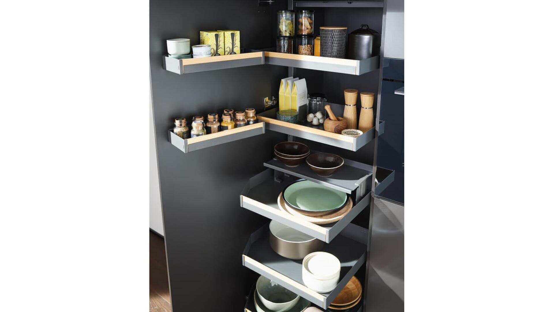 Un meuble de cuisine moderne avec quatre étagères coulissantes en forme de L qui permettent de ranger les assiettes, les bols, les pots, les épices, les bouteilles, les tasses et les petits récipients de cuisine.