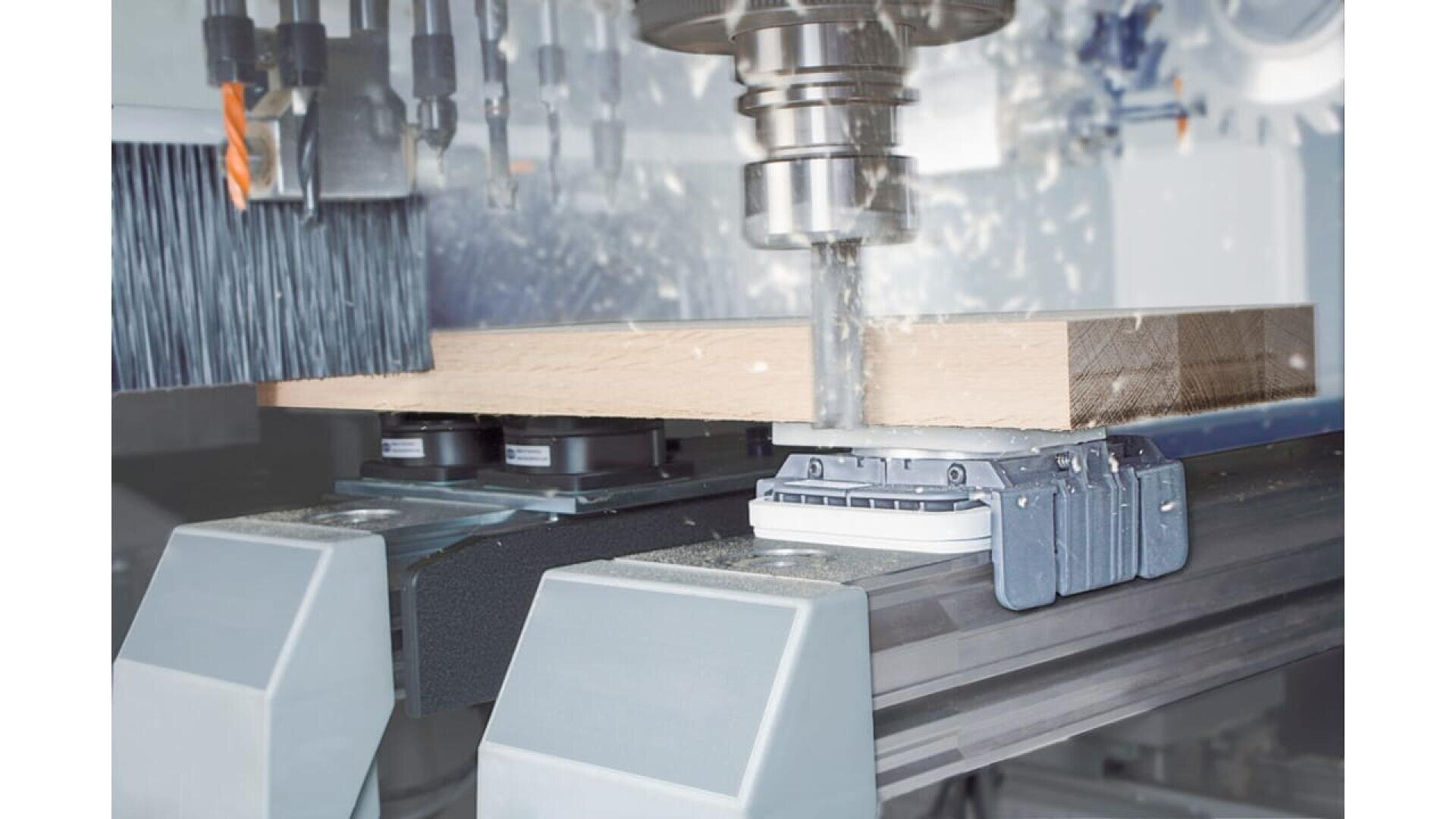 Une machine à commande numérique perce une pièce de bois, avec des copeaux de bois, sur une ligne de production automatisée moderne.