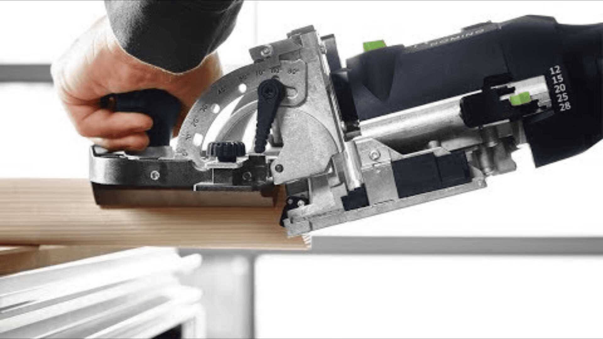 Nahaufnahme einer Person, die mit einem elektrischen Abrichtwerkzeug in die Kante eines Holzbretts schneidet, um das Holz für das Abbinden vorzubereiten. Die Szene konzentriert sich auf das Werkzeug und die Hand des Benutzers.