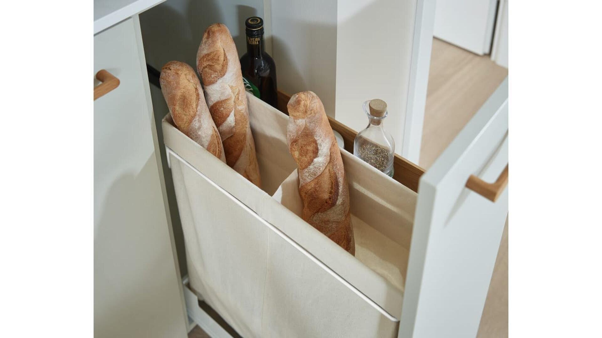 Trois baguettes, une bouteille d'huile d'olive et un pot d'assaisonnement sont rangés verticalement dans un compartiment en tissu à l'intérieur d'un meuble de cuisine coulissant.