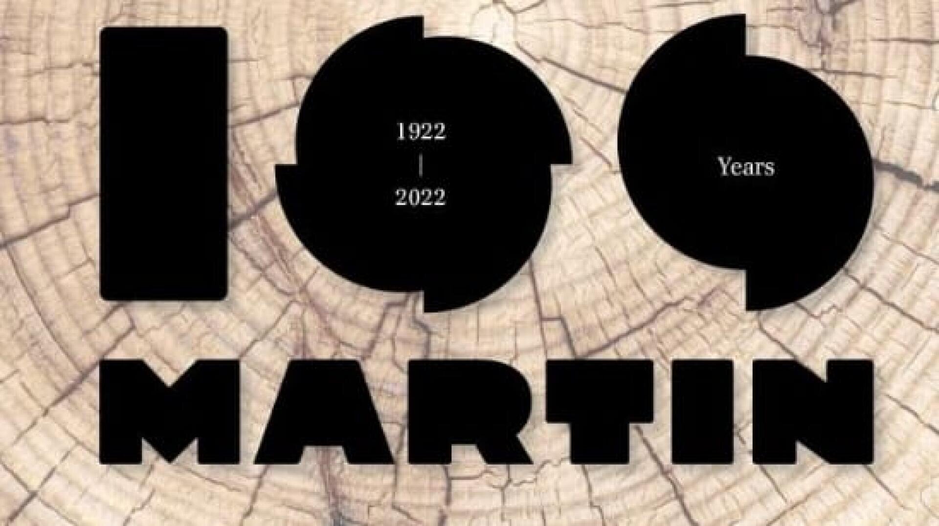 Der fettgedruckte schwarze Text auf Holzhintergrund lautet 100 Years MARTIN. Innerhalb der ersten Null steht der Text 1922 | 2022, was ein 100-jähriges Jubiläum bedeutet.