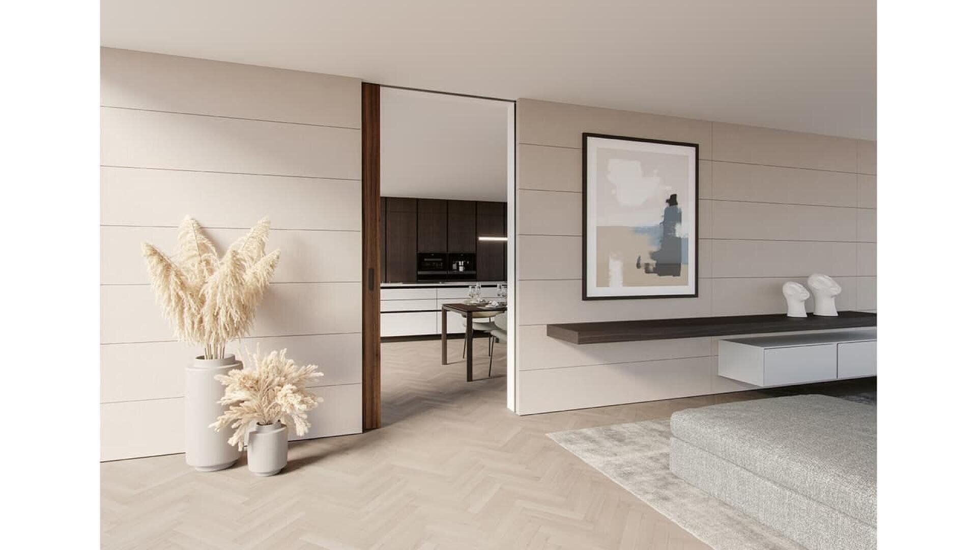 Salon moderne et minimaliste avec des murs en panneaux de bois clair, une étagère flottante, des vases décoratifs avec de l'herbe de la pampa, de l'art abstrait et une vue sur une cuisine épurée à travers une porte coulissante.