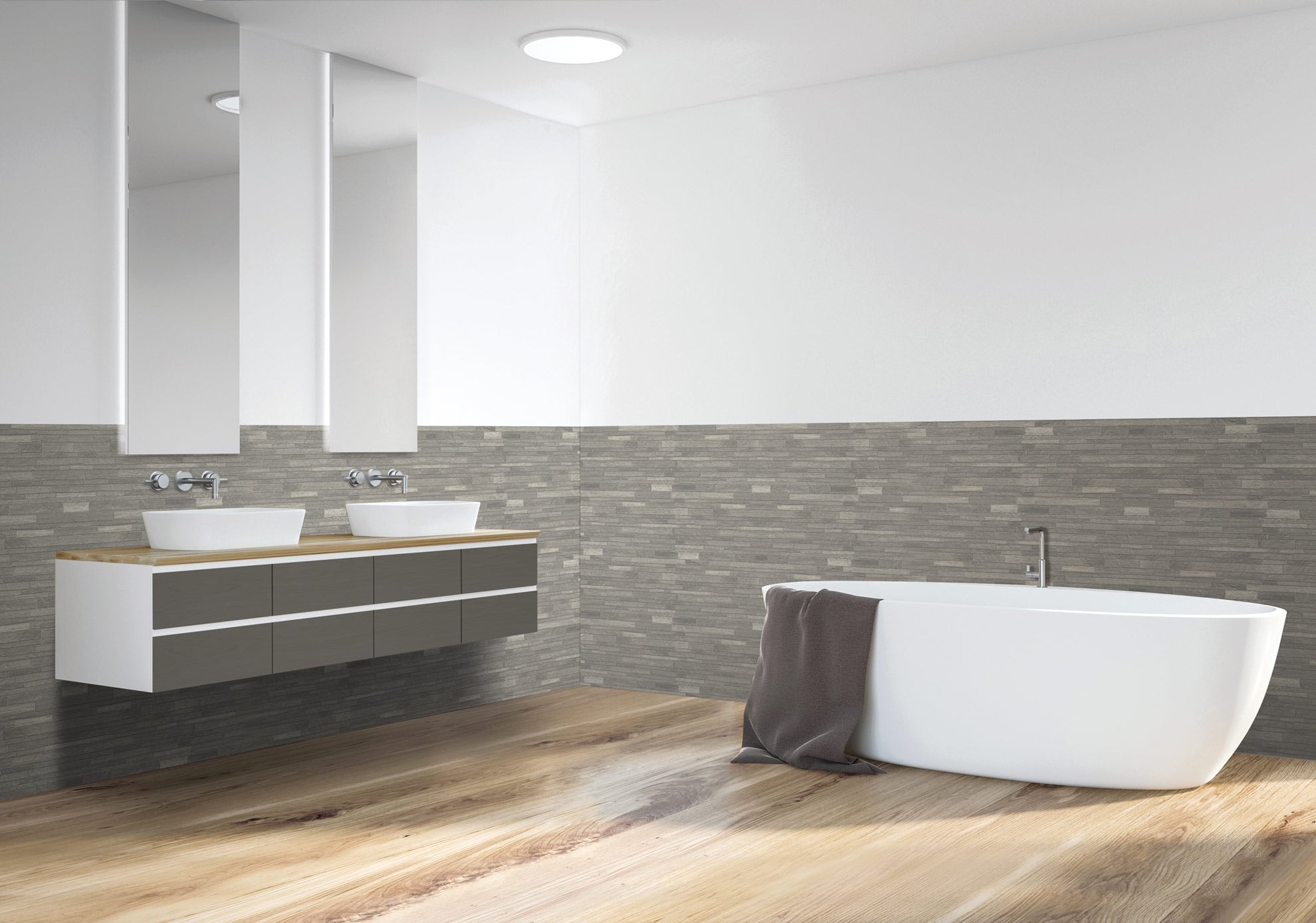 Salle de bains moderne avec un sol en bois, une baignoire blanche autoportante avec une serviette drapée sur le bord, deux lavabos avec des miroirs au-dessus, et un carrelage texturé gris sur la moitié inférieure des murs.